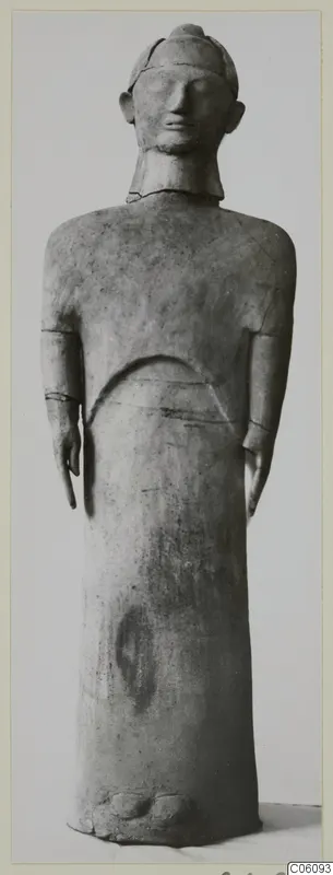 Terracotta standing figure from Ayia Irini, arms at its sides, shown full length against a plain background