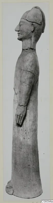 Tall standing terracotta figure in profile facing left, wearing a cap, with one arm bent forward