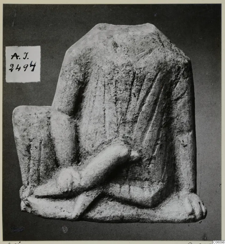 Limestone figurine fragment with a draped body and a crossed arm or leg, against a dark background