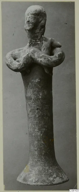 Terracotta figurine from Ayia Irini with arms folded across its chest, on a tall body with a flared base