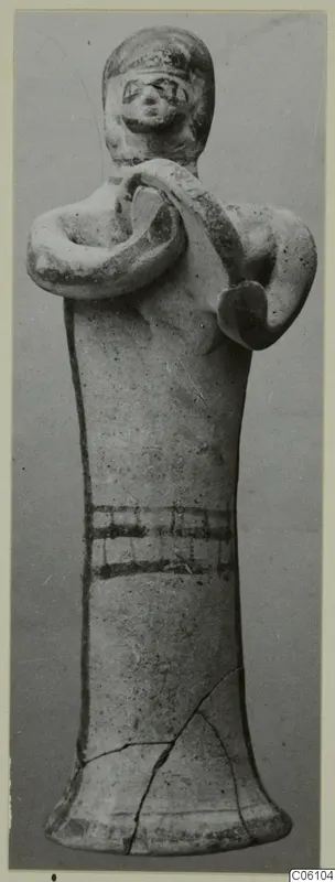 Terracotta figurine from Ayia Irini, arms bent with hands at the chest holding a curved band over one shoulder