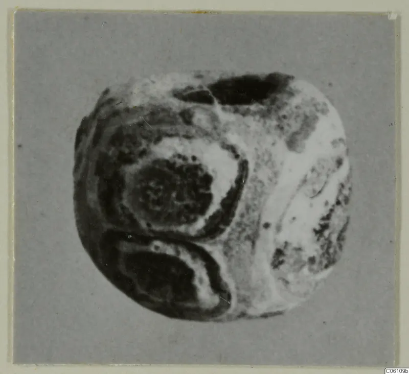 Close photograph of a rounded object with a hole near the top and dark oval banding across its surface