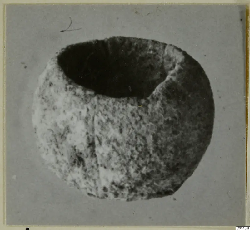 Bone bead from Ayia Irini, a rounded object with a large opening on top, photographed on grey