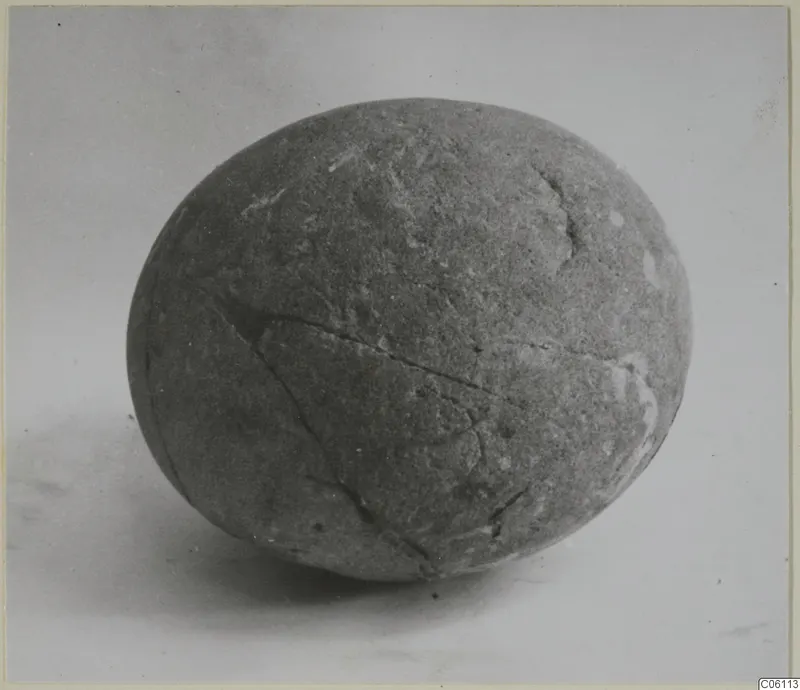 Egg-shaped grey stone, recorded as a cult stone, with cracks running across its surface
