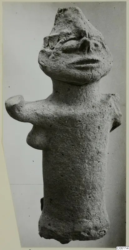 Terracotta figure from Ayia Irini with a cylindrical body, stub arms and a modelled face, seen against a plain grey background