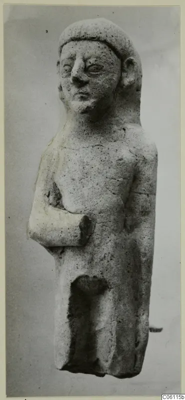 Terracotta statuette of a standing figure with one arm bent across the body, shown against a plain grey backdrop
