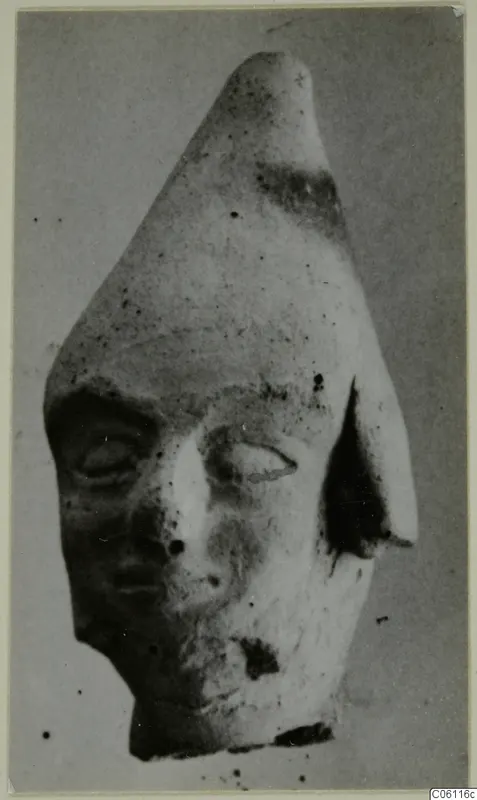 Terracotta figurine head with a tall pointed top, one ear and a broken lower edge, from Ayia Irini