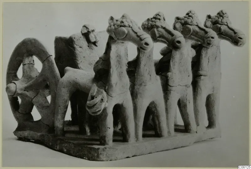 Terracotta model with a ring-shaped wheel at left and four horse-like heads in a row on a rectangular base