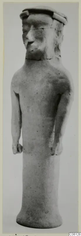 Standing terracotta figure with a cylindrical body, arms held at its sides and a flat-topped headdress from Ayia Irini