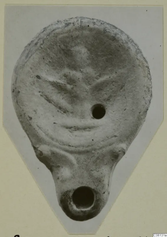 Terracotta lamp from Soli, seen from above, with raised decoration on the disc and a nozzle at the base.