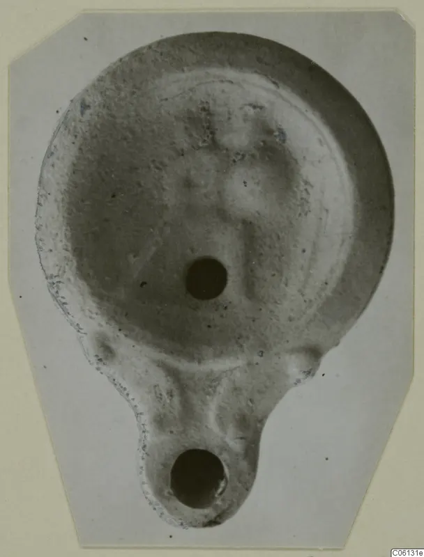 Terracotta oil lamp from Soli, photographed from above, with a filling hole and a nozzle with a wick hole at the lower end.