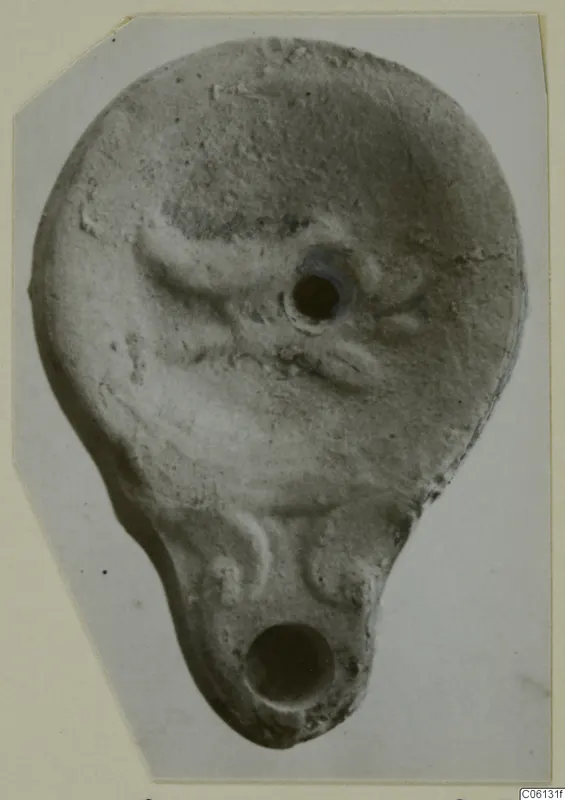 Terracotta oil lamp with a filling hole on top and a nozzle at the lower end.