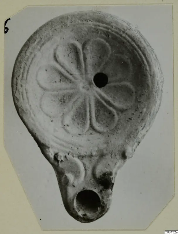 Terracotta oil lamp with a petal-like pattern around the filling hole, from Soli.