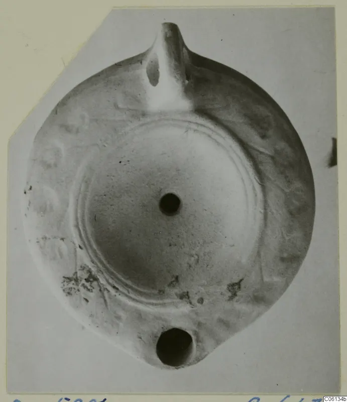 Terracotta oil lamp with a nozzle at the top and a filling hole, seen from above.
