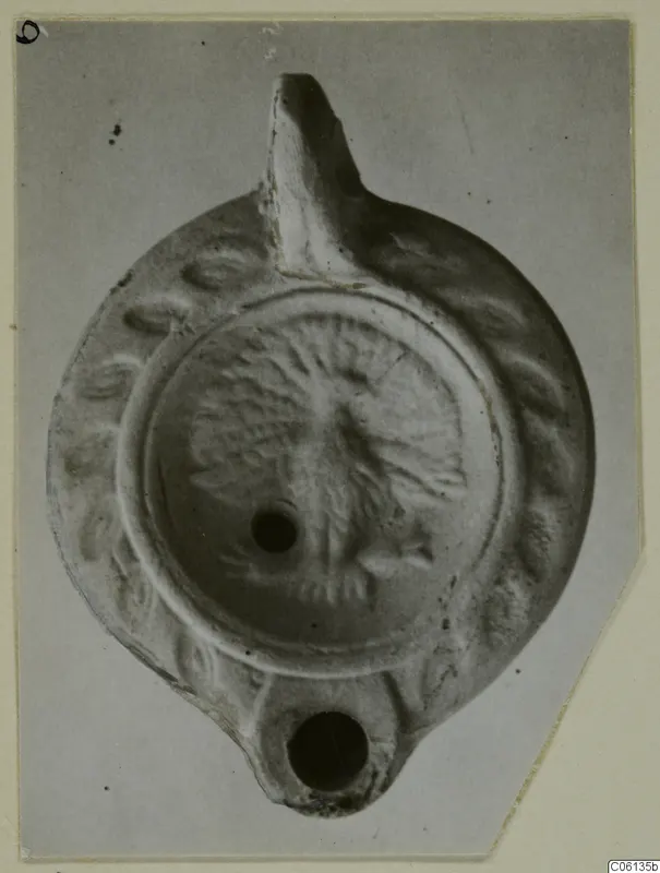 Terracotta oil lamp with a raised relief disc and a long nozzle, seen from above.