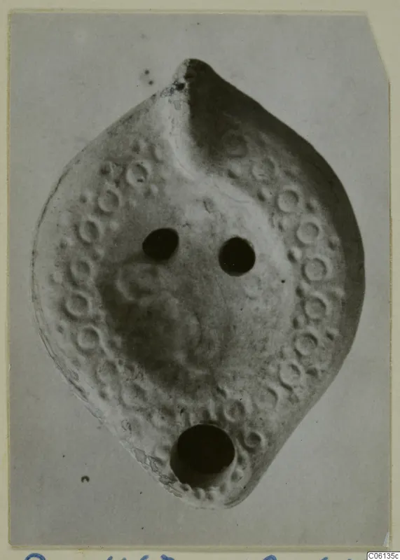 Terracotta lamp with a ring of raised circles around its rim, two filling holes and a spout hole at the base.
