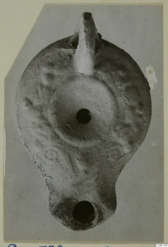 Terracotta oil lamp seen from above, with a tapering nozzle at the top and a round filling hole in the centre