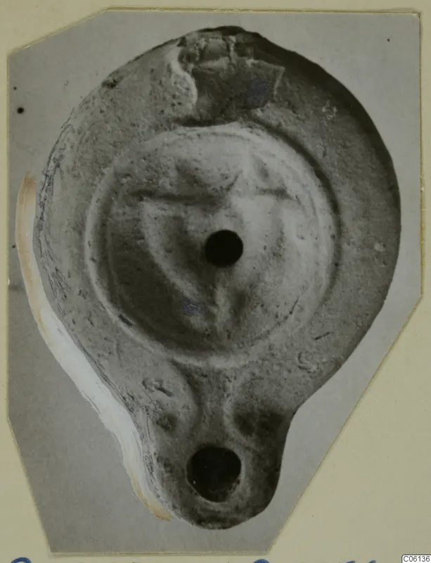 Terracotta oil lamp with a filling hole and a nozzle at the lower end, seen from above.
