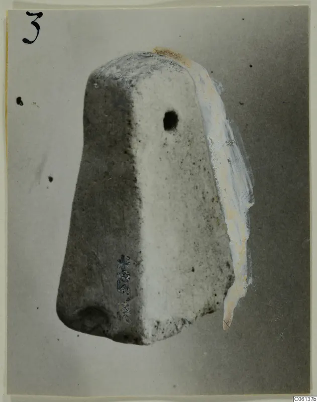 Terracotta find: a tapering block-shaped object with a round hole in one face, photographed against a grey backdrop.
