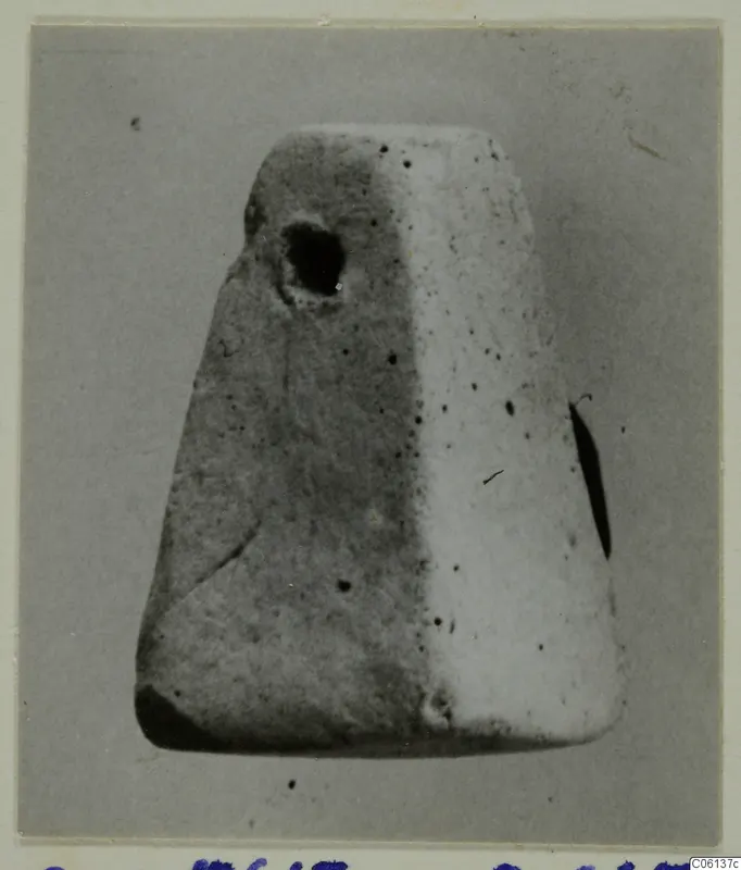 Tapering terracotta object with a round hole near its top, photographed on a grey card mount
