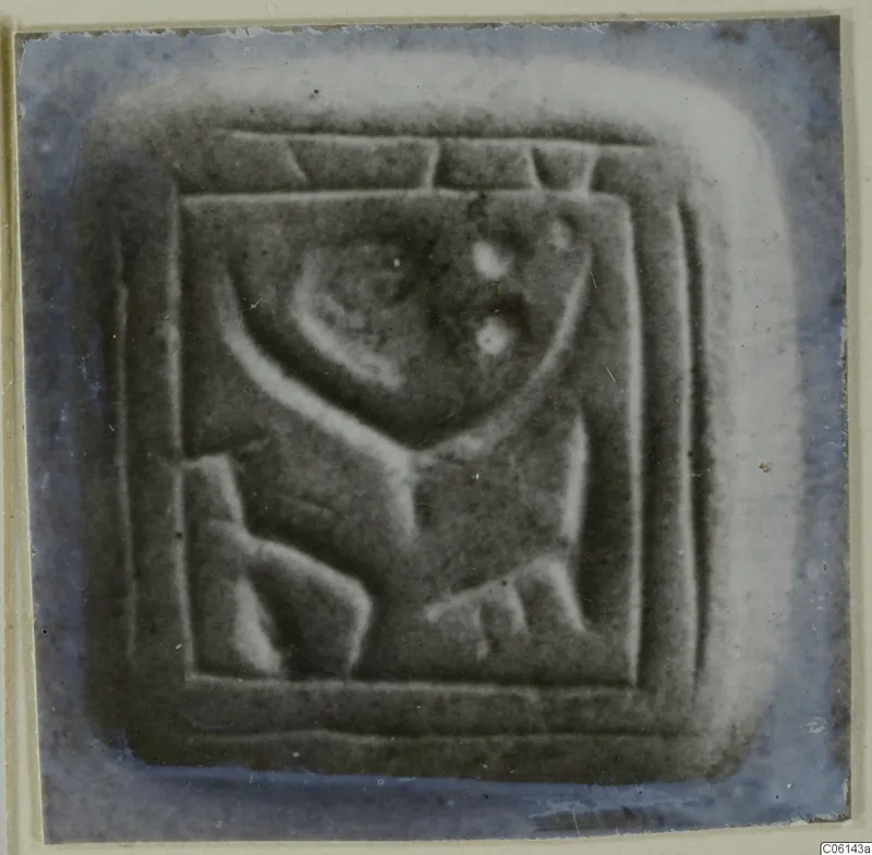 Square stone seal with a raised carved design inside a bordered frame.