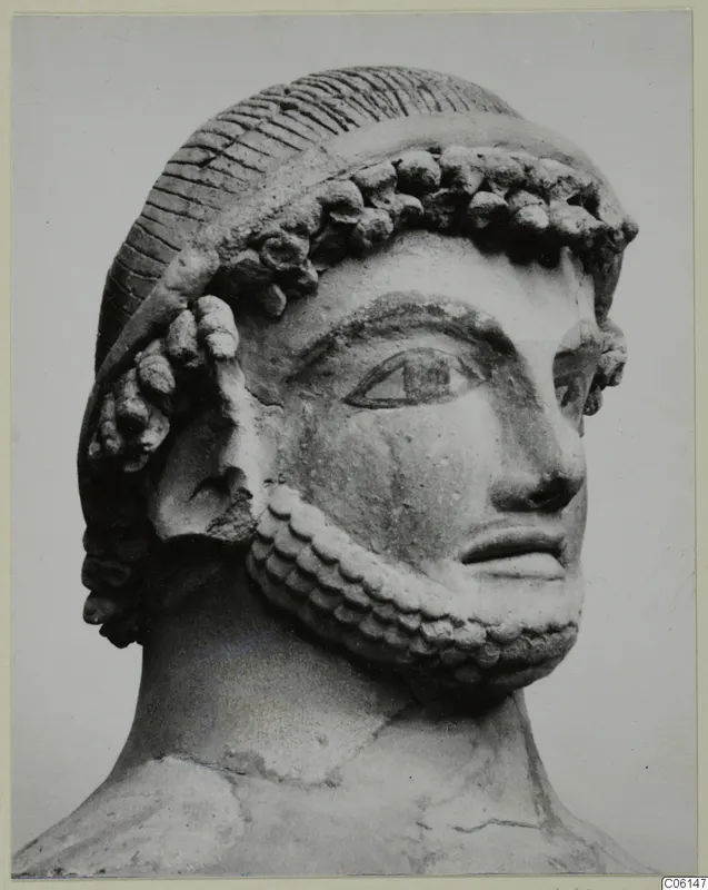 Bearded head with curled hair band, sculpted in a pale material, shown in three-quarter view