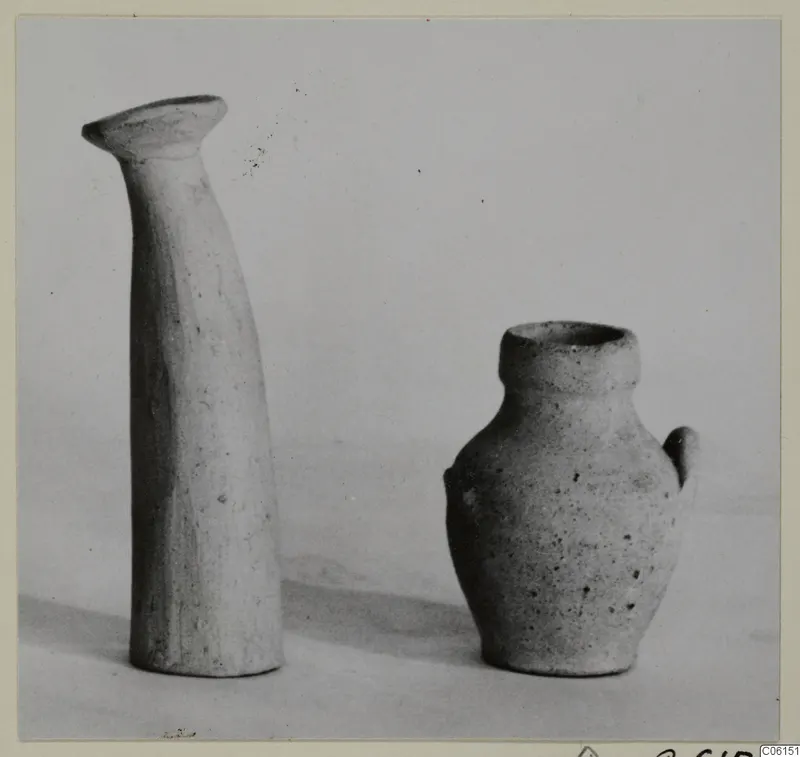 Ayia Irini pottery: a tall narrow vessel with a flared rim beside a small jug with a loop handle.