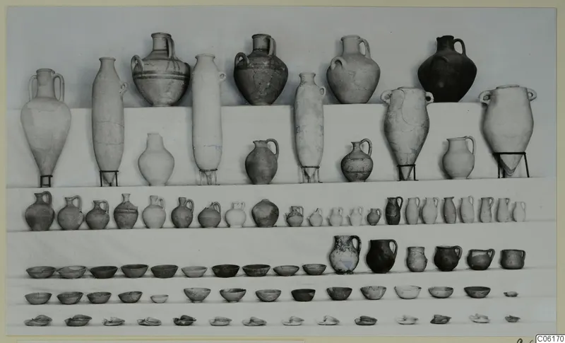 Rows of pottery vessels from Vouni Tomb 1: large jugs and amphorae at the top, with smaller jugs, bowls and saucers in rows below.