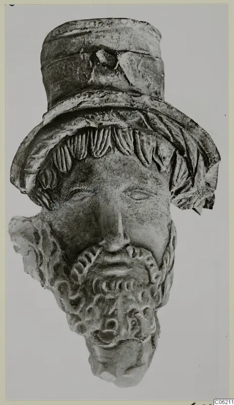 Terracotta head of a bearded figure wearing a tall cylindrical headdress, broken at the neck and left side
