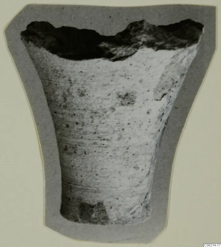 Broken fragment of a vessel, wider at the top, shown on a grey card mount