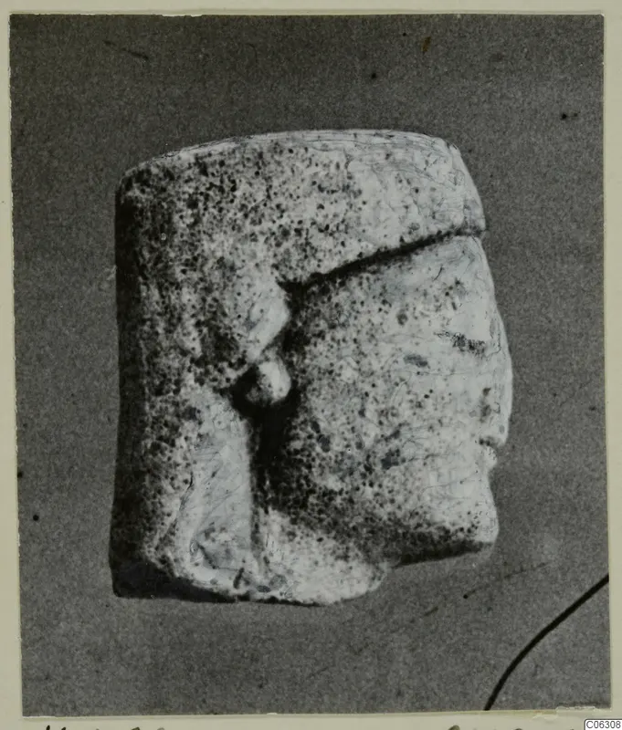 Limestone statuette fragment with a head in profile facing right and a pitted surface
