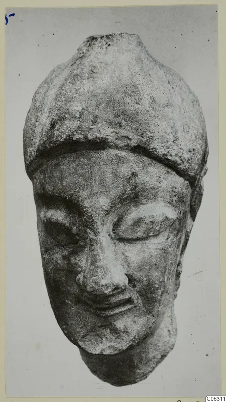 Limestone head from Kition with a rounded cap and lowered eyes, photographed frontally.