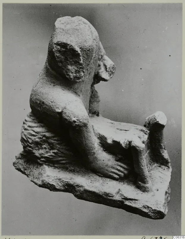 Limestone statuette of a seated figure shown in profile, one arm bent down over a rough base