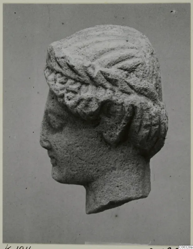 Limestone head sculpture in profile facing left, hair in wavy bands under a broad band, from Kition