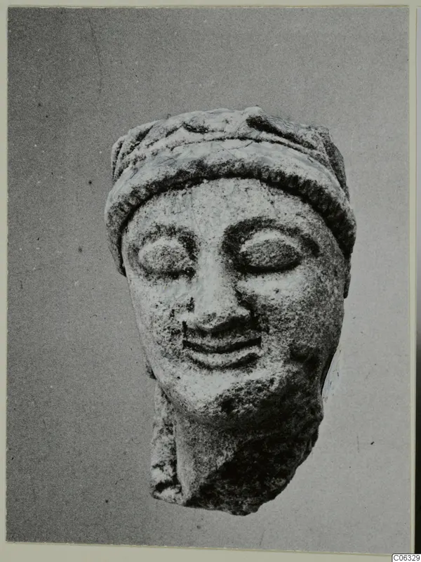 Limestone head of a statue with a wide band across the top of the head and eyes closed.