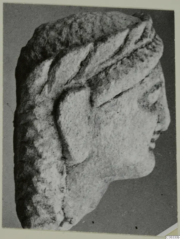 Limestone head from Kition in profile facing right, with a carved headdress and textured hair