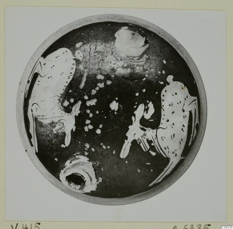 Interior of a shallow round pottery vessel seen from above, with dark glaze and pale painted motifs