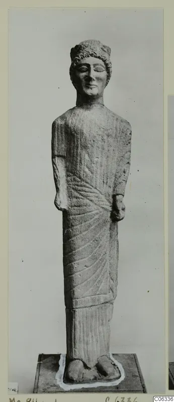 Limestone statue of a standing figure from Mersinaki, with curled hair and a draped garment with radiating folds.