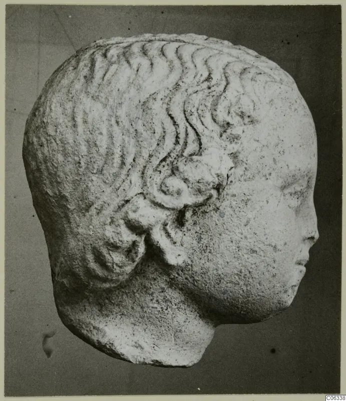 Carved stone head with wavy hair and a curled lock above the ear, from Mersinaki