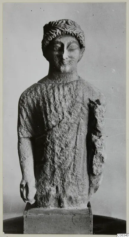 Limestone statue from Kition of a standing figure with a leafy band in its hair, one arm broken away at the shoulder