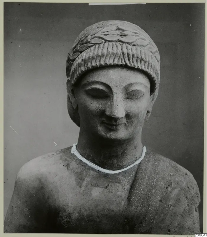 Limestone sculpture head and shoulders from Kition, with a carved leaf-patterned headdress and downcast eyes