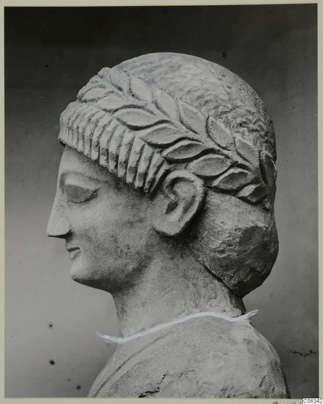 Limestone head in profile facing left, with a carved band of leaves across the hair above the forehead
