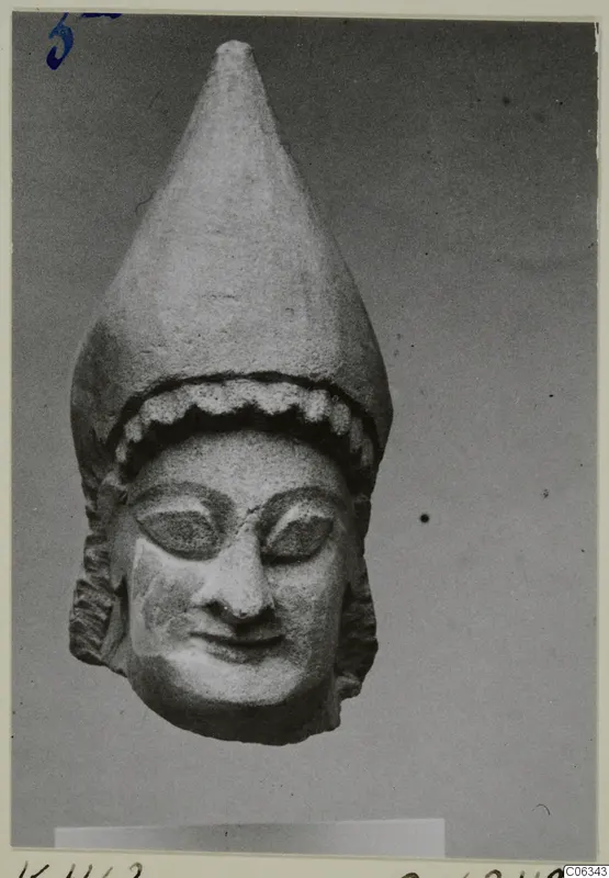 Limestone head statue from Kition with a tall conical headdress and a faint smile