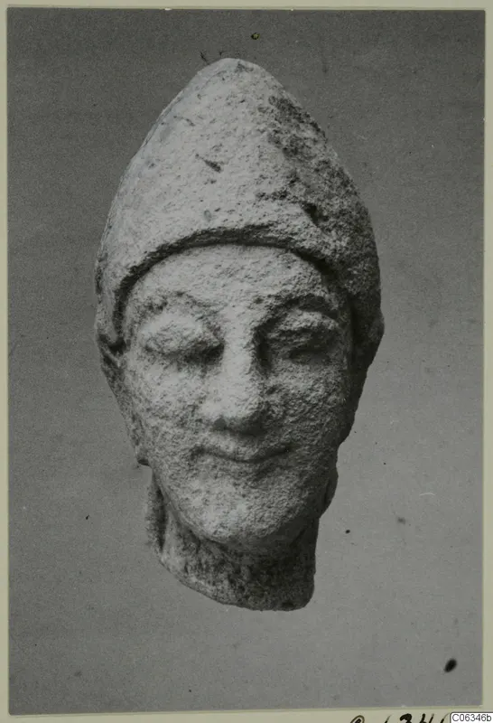 Limestone head fragment from Kition with a tall pointed cap, seen from the front