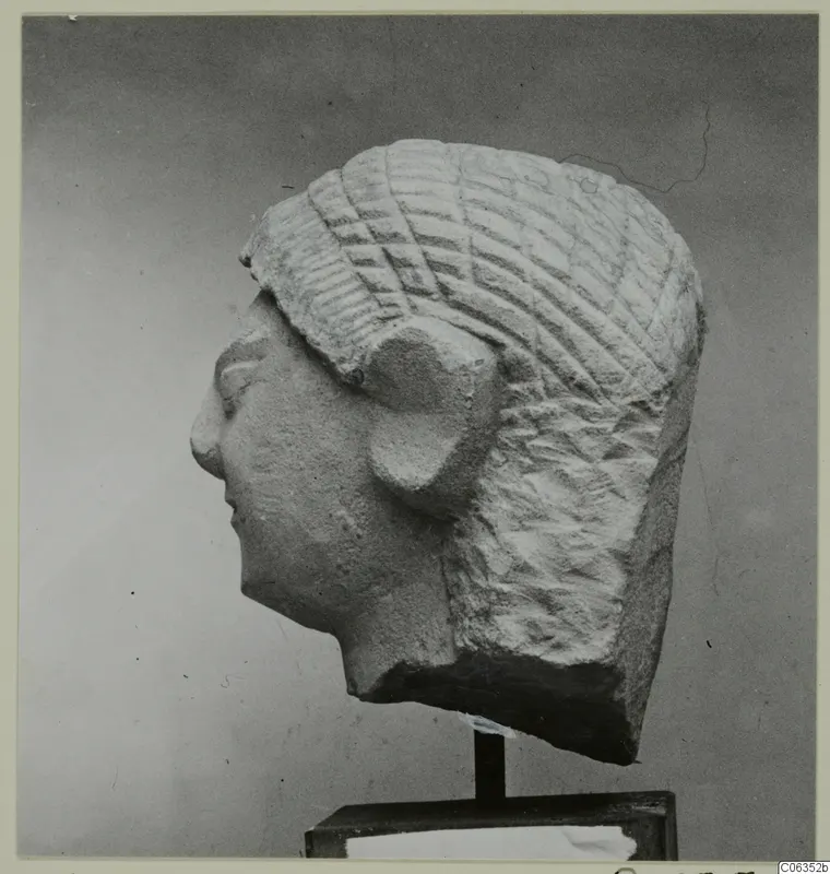 Limestone head statuette in profile facing left, with incised hair, mounted on a dark stand from Kition
