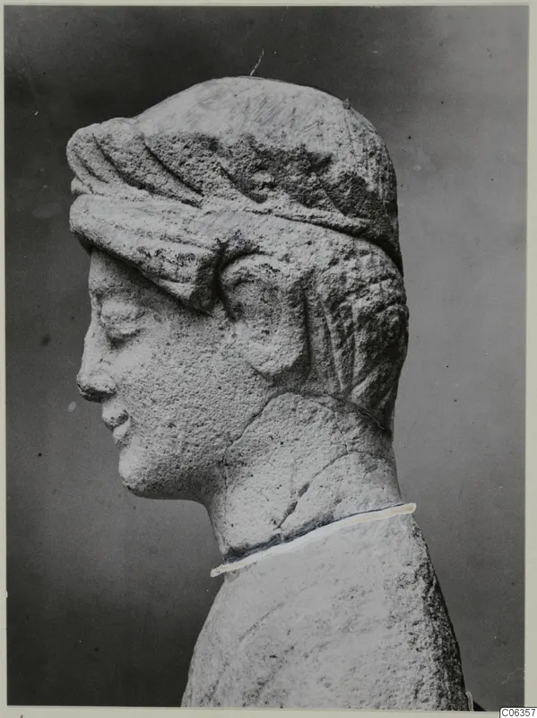 Limestone head sculpture in profile facing left, with a band over the hair and a neck that is cracked and joined