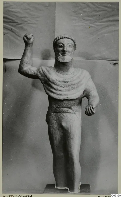 Limestone statue of a bearded standing male figure with one fist raised, from Kition