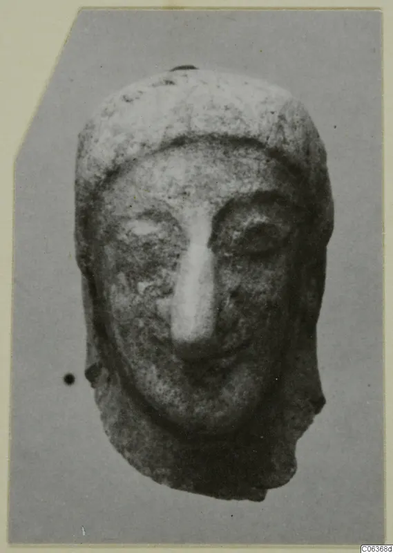Head of a small terracotta figurine with a long straight nose and deep-set eyes, from Vouni, shown against a grey backdrop
