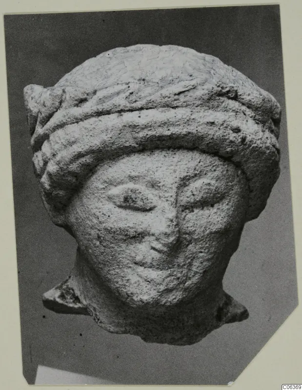 Limestone head from Vouni with a thick banded headdress, shown in a photograph on a card mount.