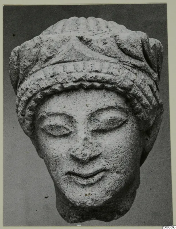 Limestone head from Vouni with downcast eyes and a ridged headdress, shown from the front